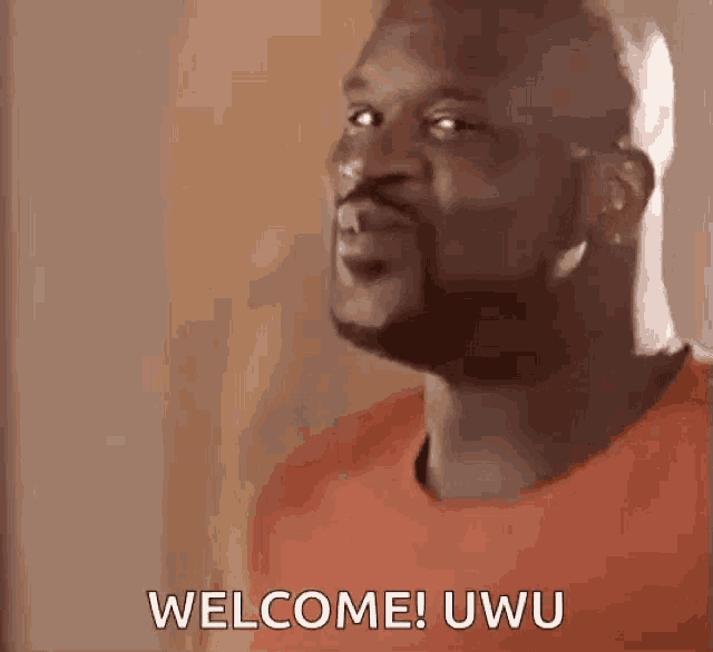 a man with a beard is standing in front of a wall and saying welcome ! uwu .