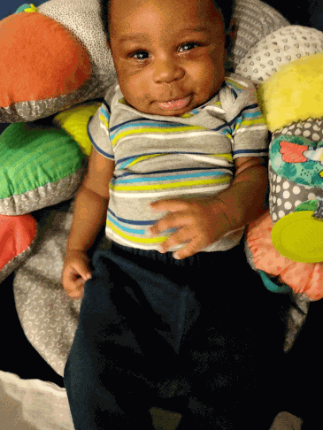 a baby in a striped shirt is sitting in a crib