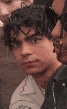 a man with curly hair looks at the camera