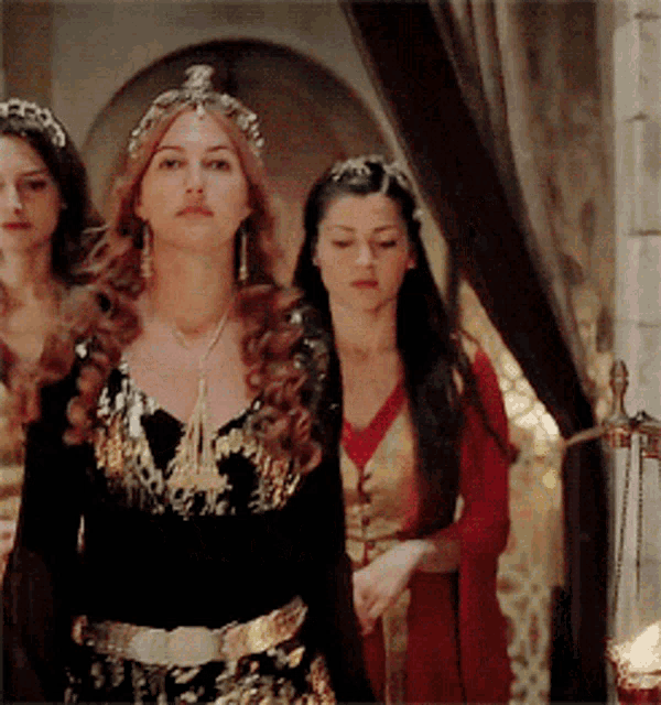 three women are standing next to each other and one has a tiara on her head