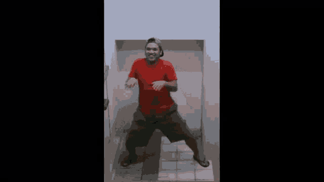 a man in a red shirt and a hat is dancing in a bathroom