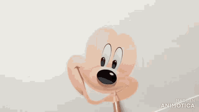 a person is drawing a mickey mouse face with a pencil on a white paper .