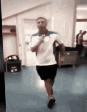 a man in a white shirt and black shorts is running in a room .