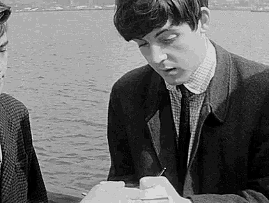 a black and white photo of two young men sitting on a boat .