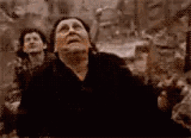 a woman in a black dress is looking up at something in the sky .