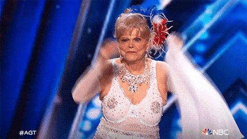 a woman in a white bra and white gloves is dancing on a stage in front of a blue background .