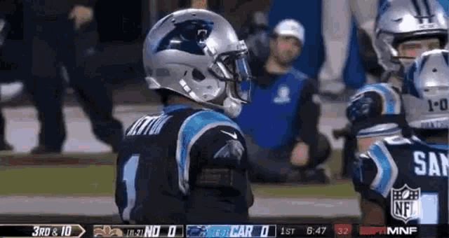 a football player wearing a helmet is standing on a field during a game .