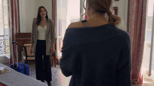 a woman is standing in front of a mirror with a blue suitcase