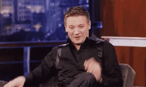 a man in a black shirt is sitting in a chair on a stage .