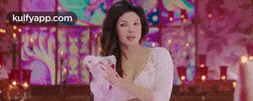 a woman is holding a stuffed animal in her hands in front of a colorful wall .