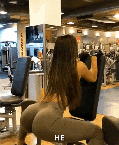 a woman squatting on a machine in a gym with the word he above her