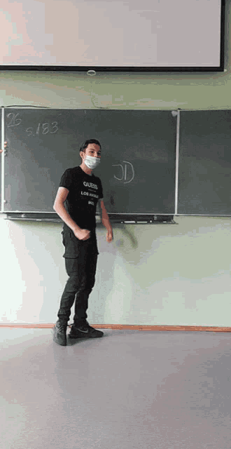 a man wearing a mask is standing in front of a blackboard that says 26.5.183