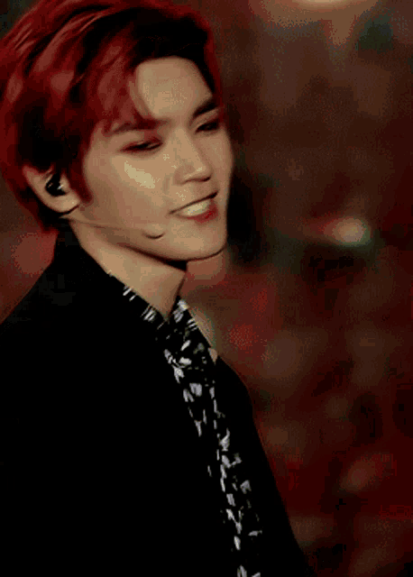 a man with red hair is wearing a black jacket and a microphone