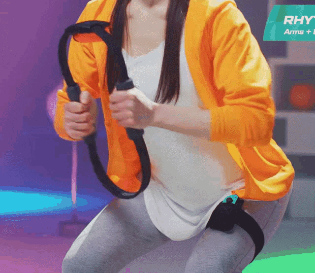 a woman in an orange jacket squatting with a ring in her hands