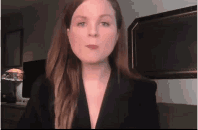 a woman with long hair is wearing a black jacket and red lipstick