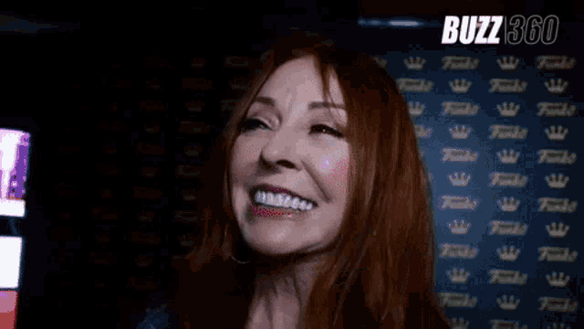 a woman with red hair is smiling in front of a wall with crowns .