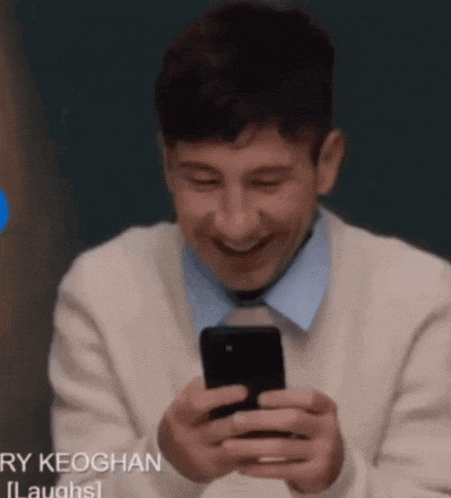 a man is laughing while looking at his cell phone