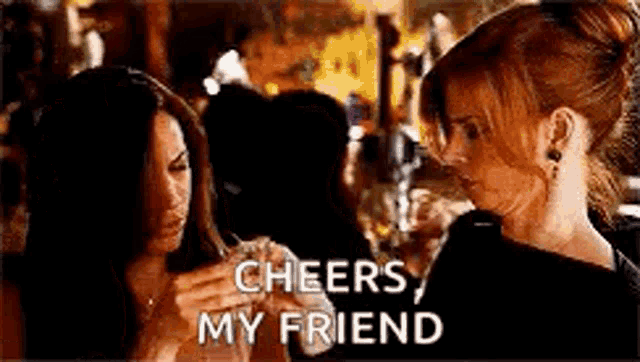 two women are standing next to each other in a bar holding glasses of alcohol .