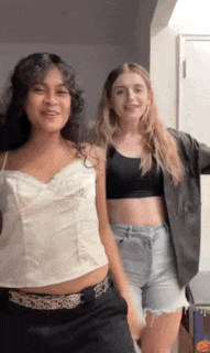 two girls are standing next to each other in a room .