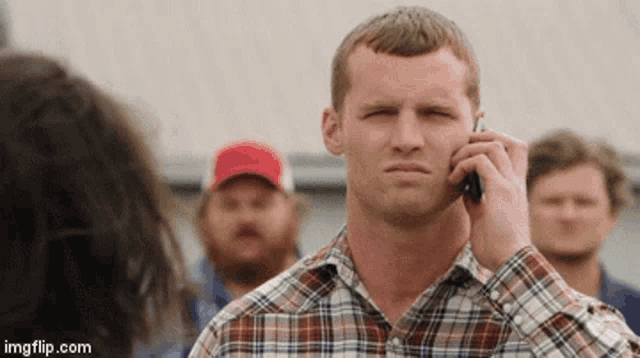 a man in a plaid shirt is talking on a cellphone