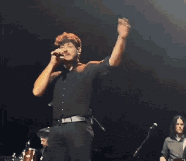 a man in a black shirt is singing into a microphone