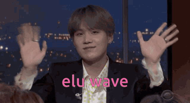 a man in a suit and polka dot shirt with the word elu wave on the bottom