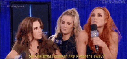 three women are sitting in front of a microphone and one of them is holding a microphone .