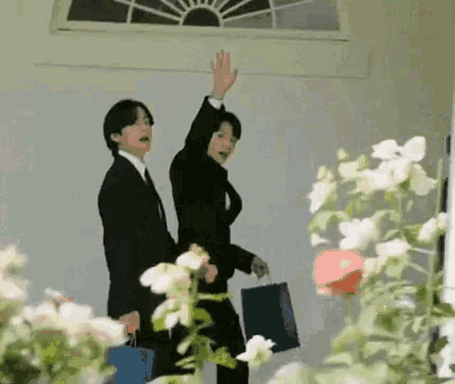 two men in suits and ties are standing next to each other in front of a window .