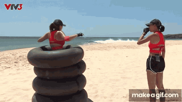 two women are standing on a beach with a stack of tire tubes and the words make a gif.com on the bottom