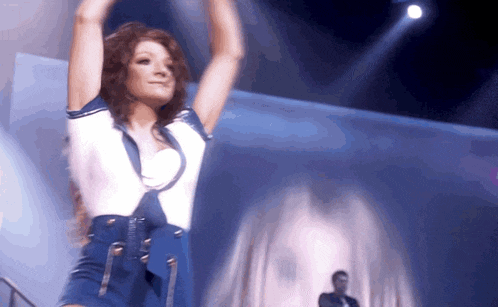 a woman in a blue and white outfit is dancing on stage