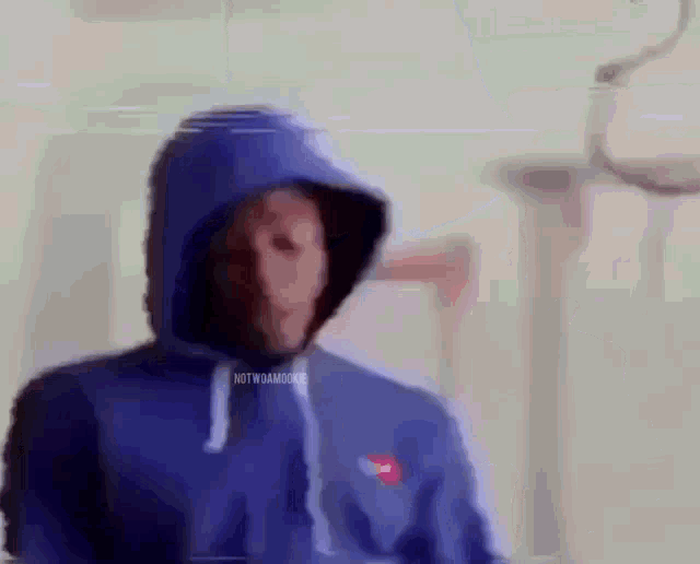 a man wearing a blue hoodie is standing in front of a lamp .