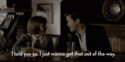 a man and a woman are sitting at a bar talking to each other while drinking beer .