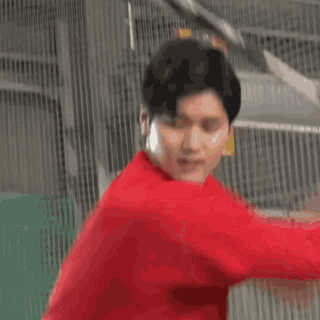 a young man in a red shirt is swinging a bat at a ball .