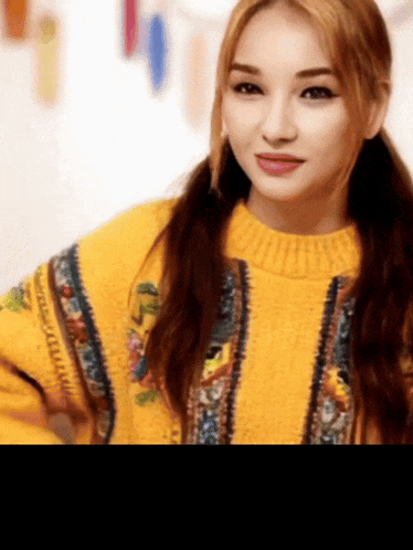 a woman wearing a yellow sweater with a floral pattern on it