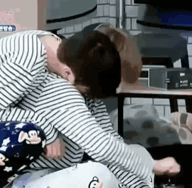 a man in a striped shirt is laying on a woman 's lap in a room .