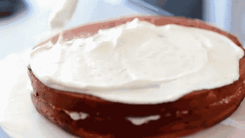 a cake is being frosted with whipped cream on a white plate