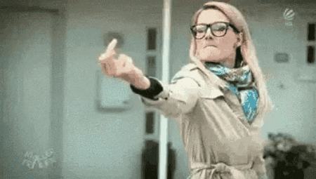 a woman wearing glasses and a trench coat is giving a middle finger .