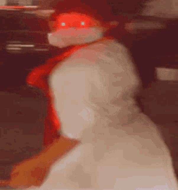a person wearing a mask and a red scarf is dancing in a dark room .