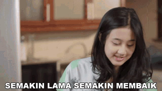 a woman in a kitchen with the words semakin lama semakin membaik written above her