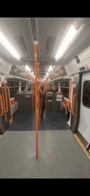 a woman is standing in the middle of an empty subway train
