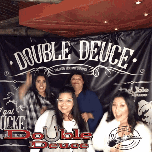 a group of women posing in front of a double deuce sign
