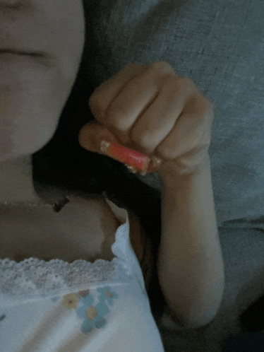 a woman in a white tank top is holding a small red object in her hand