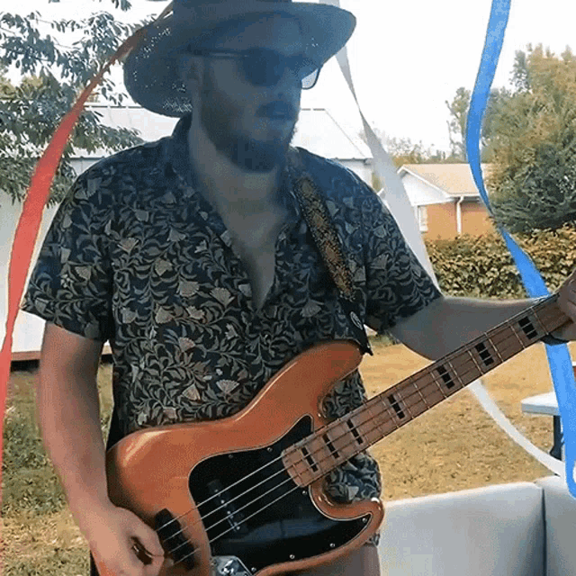 a man wearing a hat and sunglasses is playing a guitar