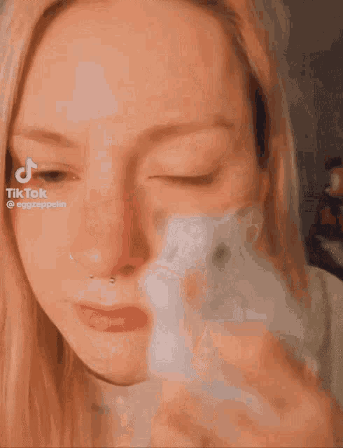 a close up of a woman 's face with a hamster in her hand