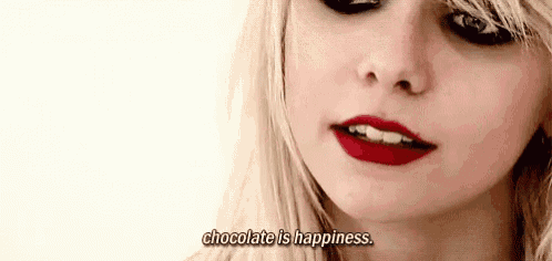 a close up of a woman 's face with the words `` chocolate is happiness '' written on the bottom .