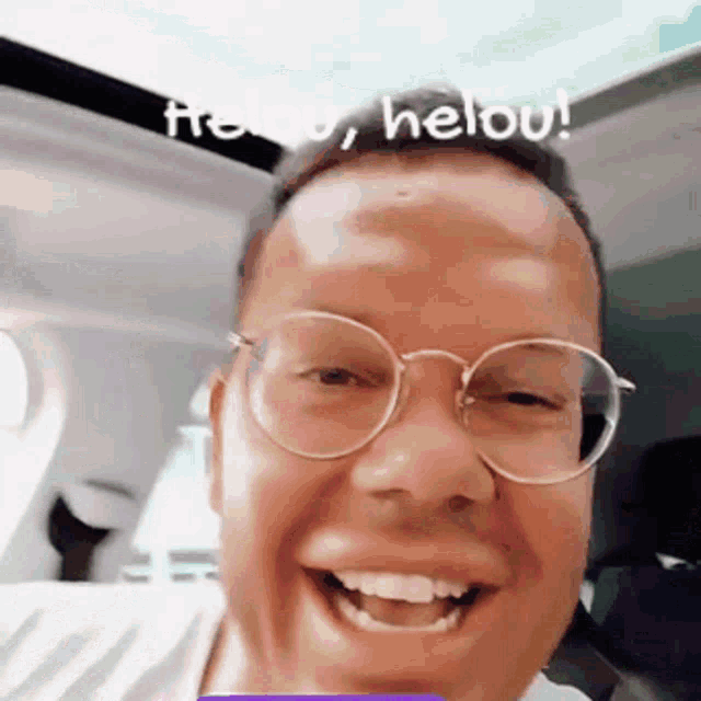 a man wearing glasses is smiling in a car with the words hellou written on the roof
