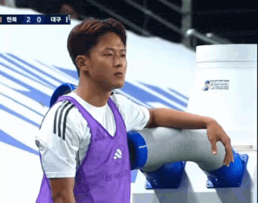 a man wearing a purple adidas vest stands next to a blue pipe