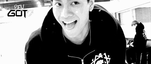 a black and white photo of a young man making a funny face with his tongue out .