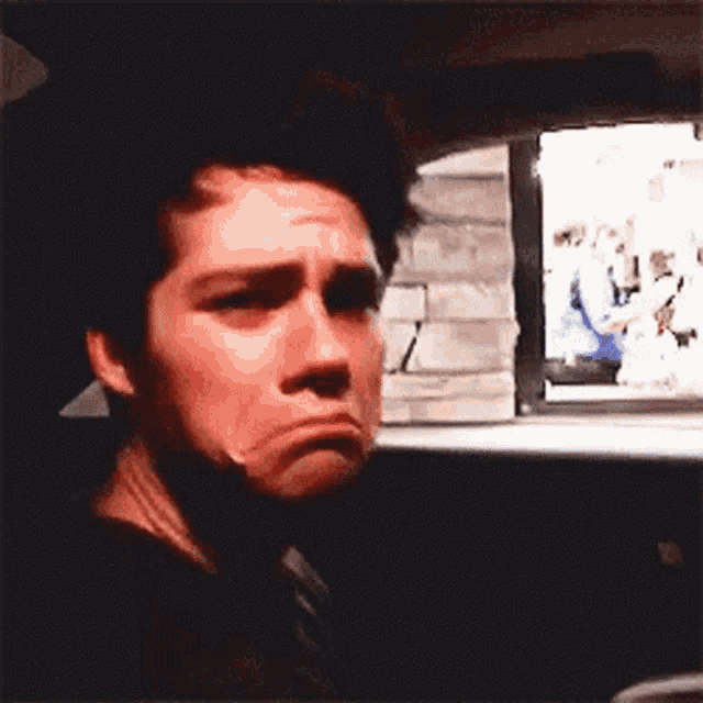 a young man is making a funny face while sitting in a car .