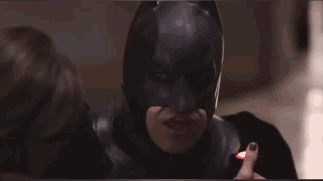 a man in a batman mask holds a flashlight in his mouth